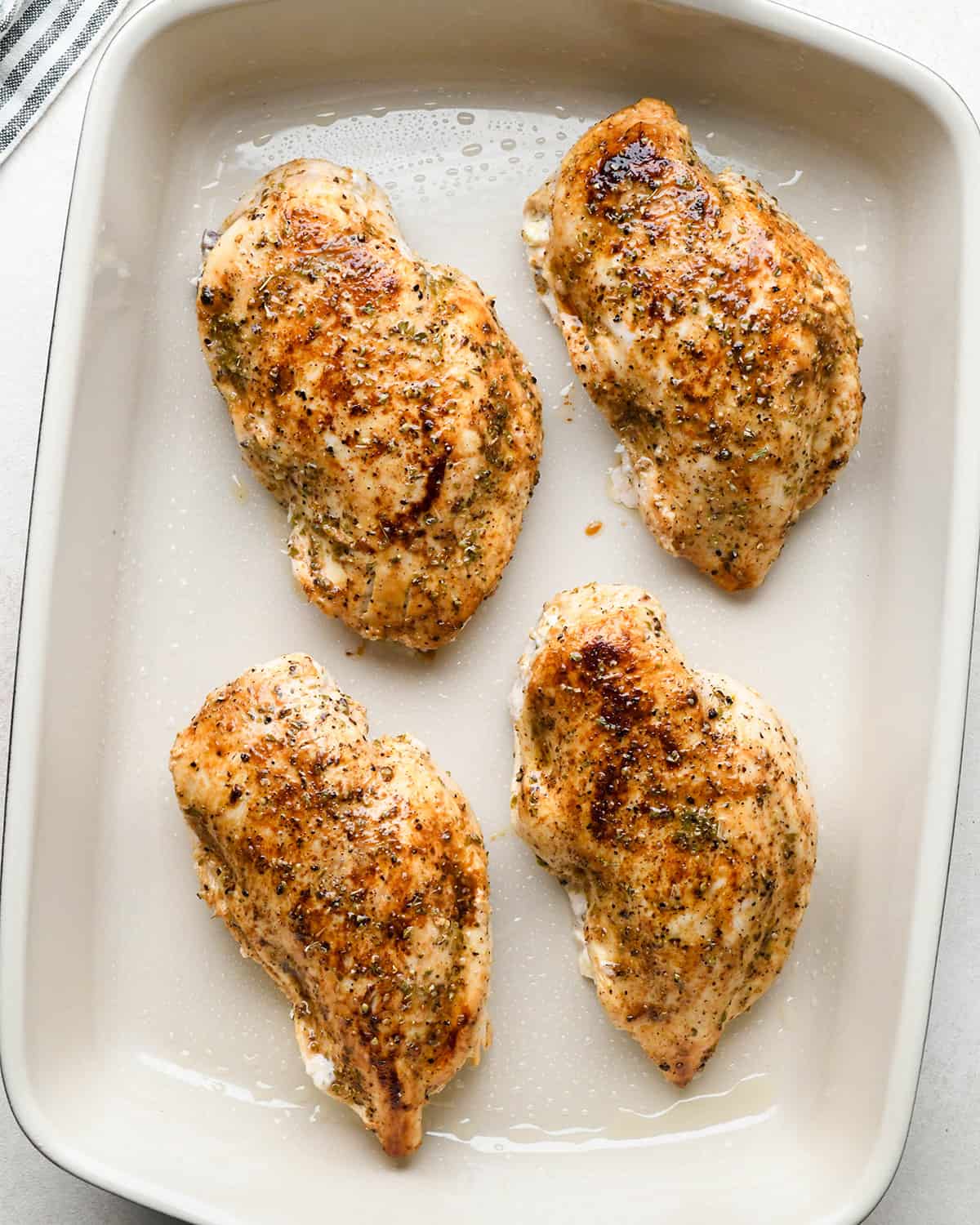 4 greek stuffed chicken breasts in a baking dish before baking