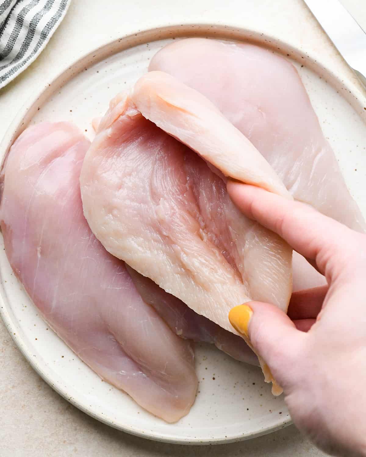 a hand showing the pocket cut into a chicken breast 