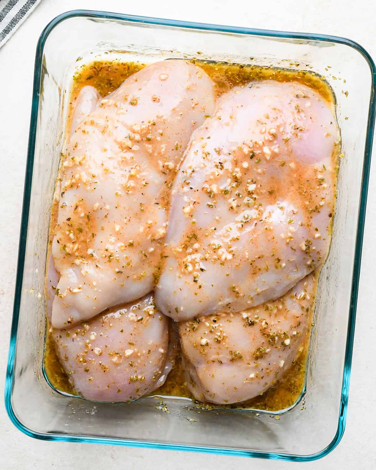 4 chicken breasts covered in marinade in a glass container