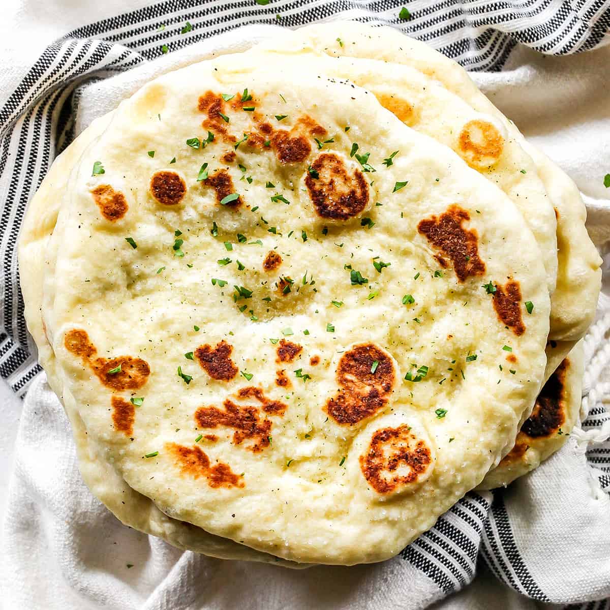 a stack of Homemade Naan Bread Recipe topped with cilantro