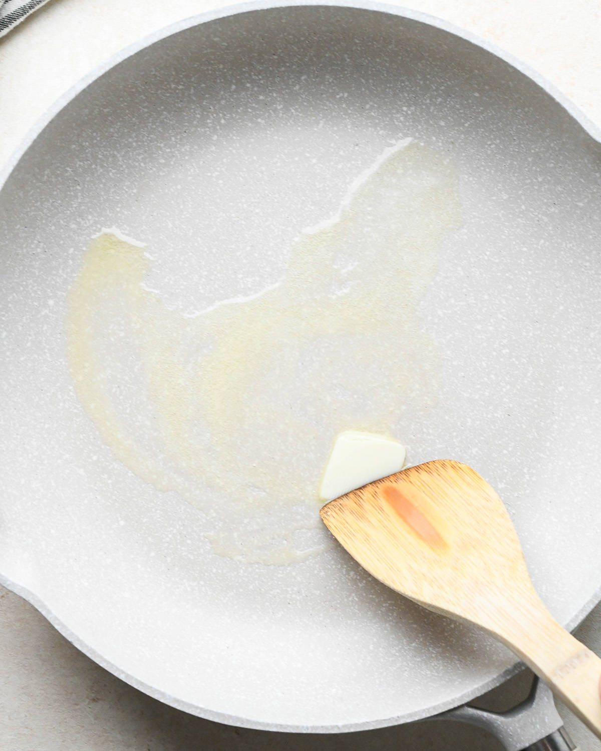 butter being melted and spread in a pan with a wooden spatula