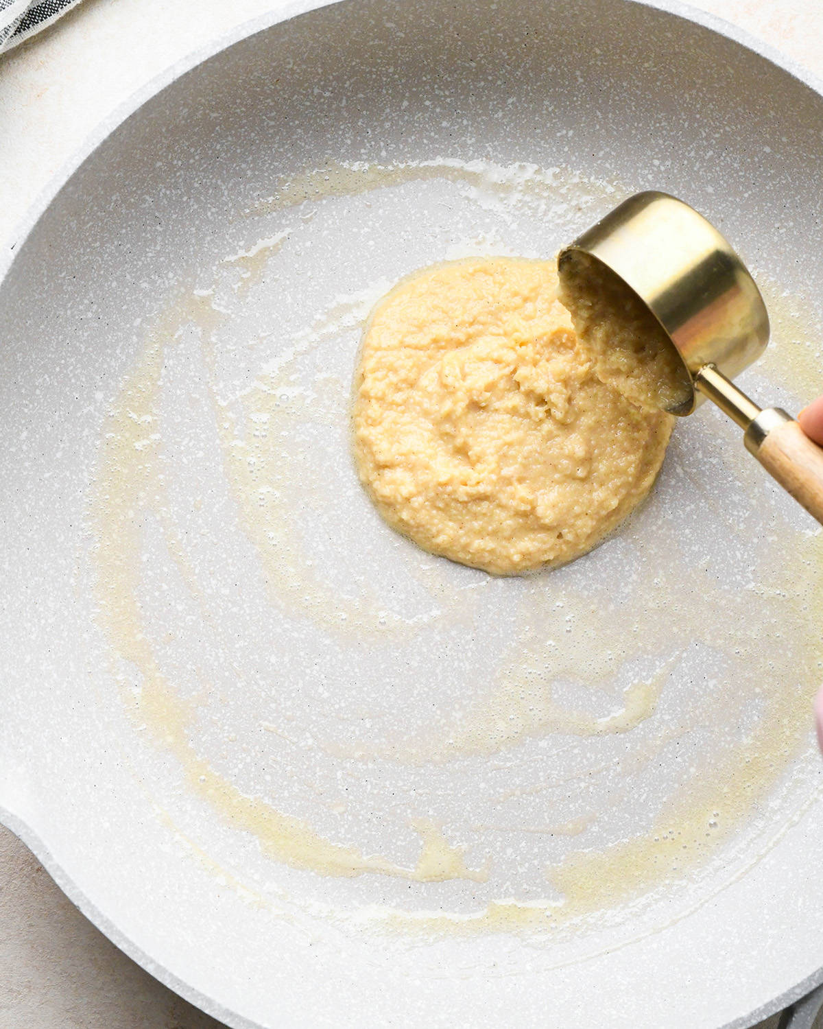 almond four pancake batter being poured onto the preheated, buttered pan