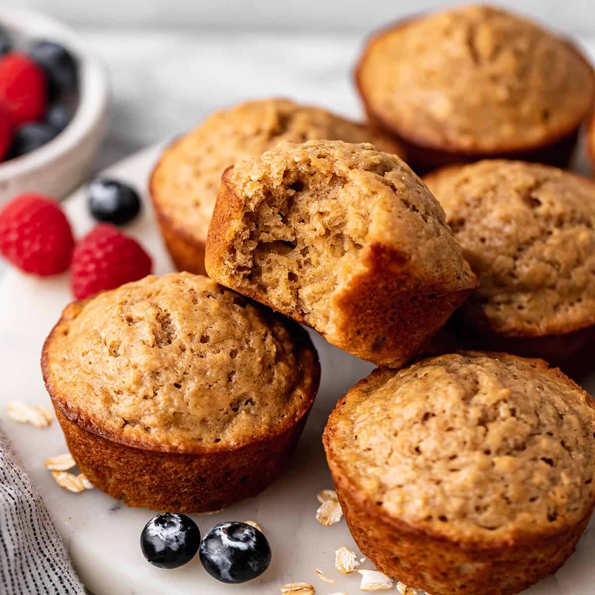 6 Oatmeal Muffins on a serving plate, one with a bite taken out of it