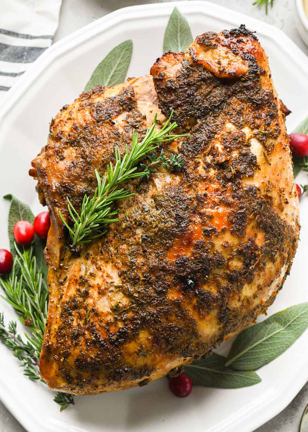 Crock Pot Turkey Breast on a serving plate garnished with herbs and cranberries