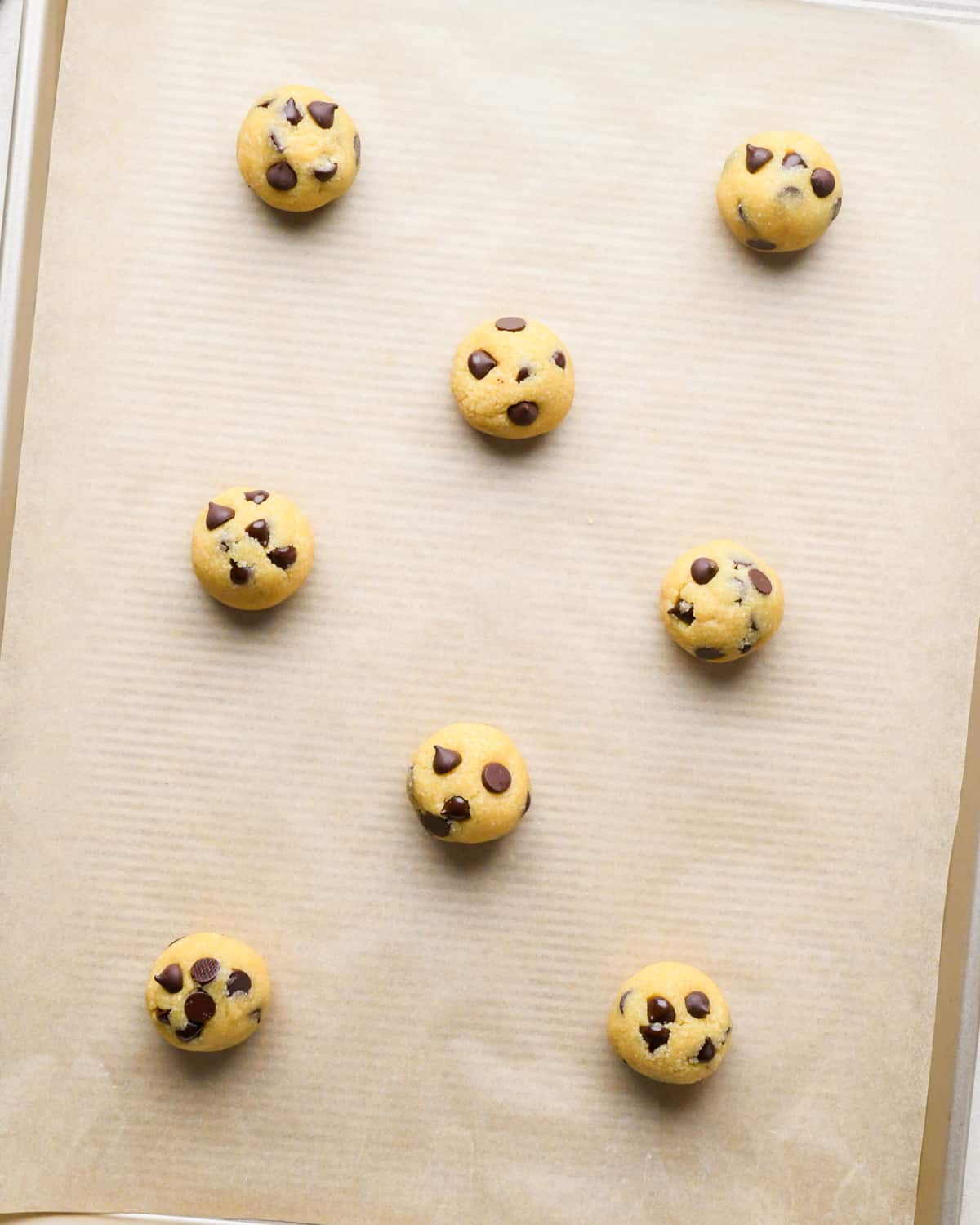 8 almond flour chocolate chip cookie dough balls on a baking sheet before baking