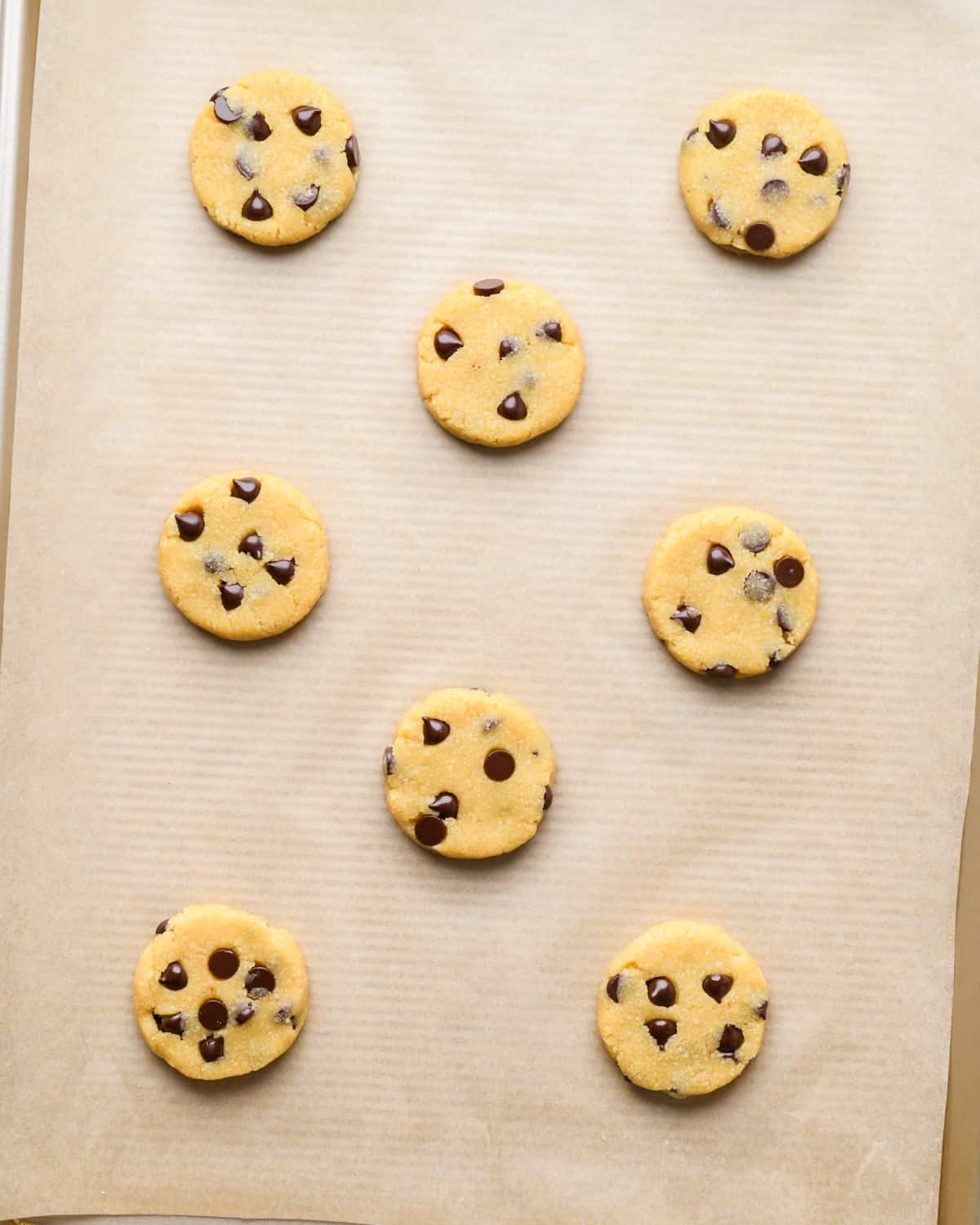 8 almond flour chocolate chip cookies on a baking sheet before baking