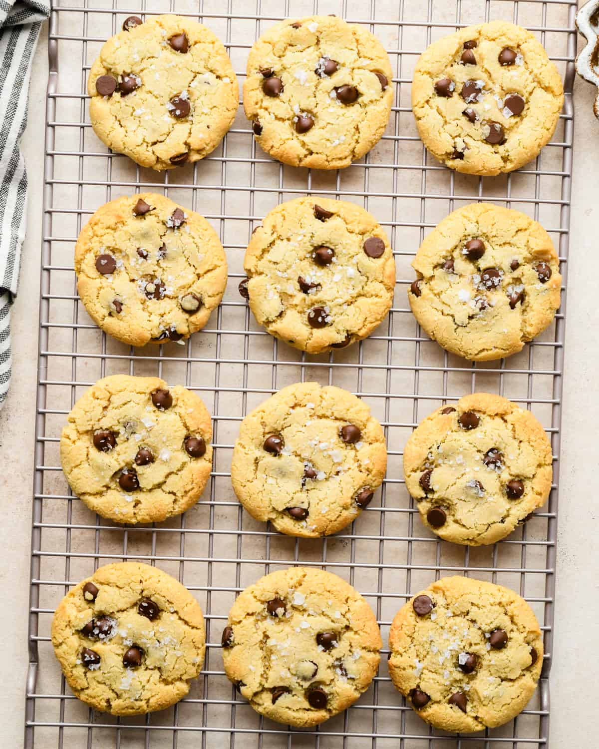 12 Almond Flour Chocolate Chip Cookies with flaky sea salt on a wire cooling rack