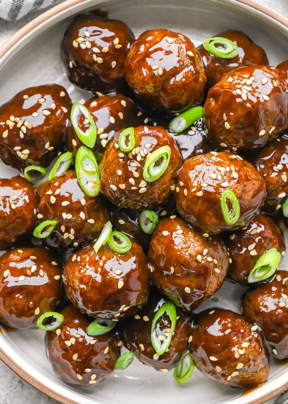 Asian Meatballs on a plate garnished with sesame seeds and green onions