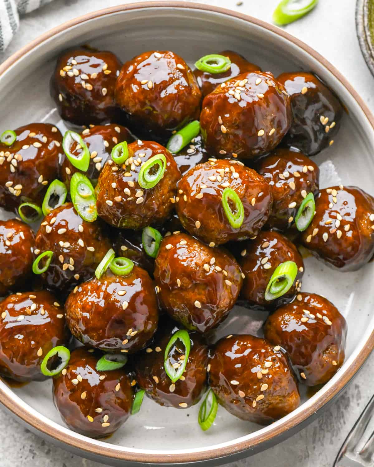 Asian Meatballs on a plate garnished with green onions and sesame seeds