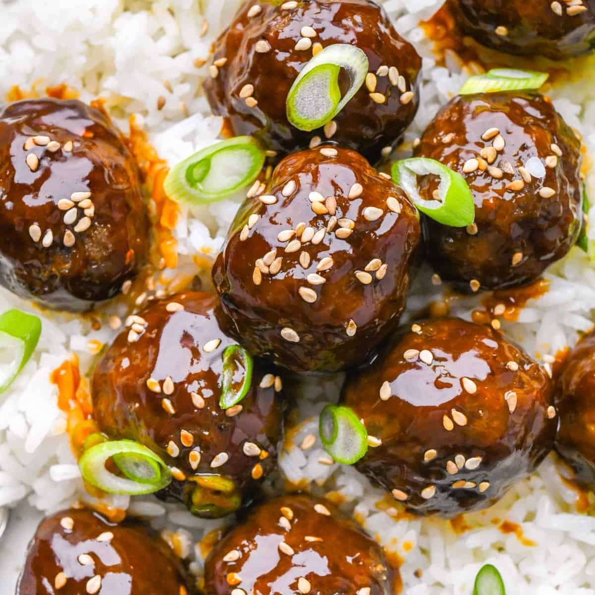 9 Asian Meatballs over rice garnished with sesame seeds and green onions