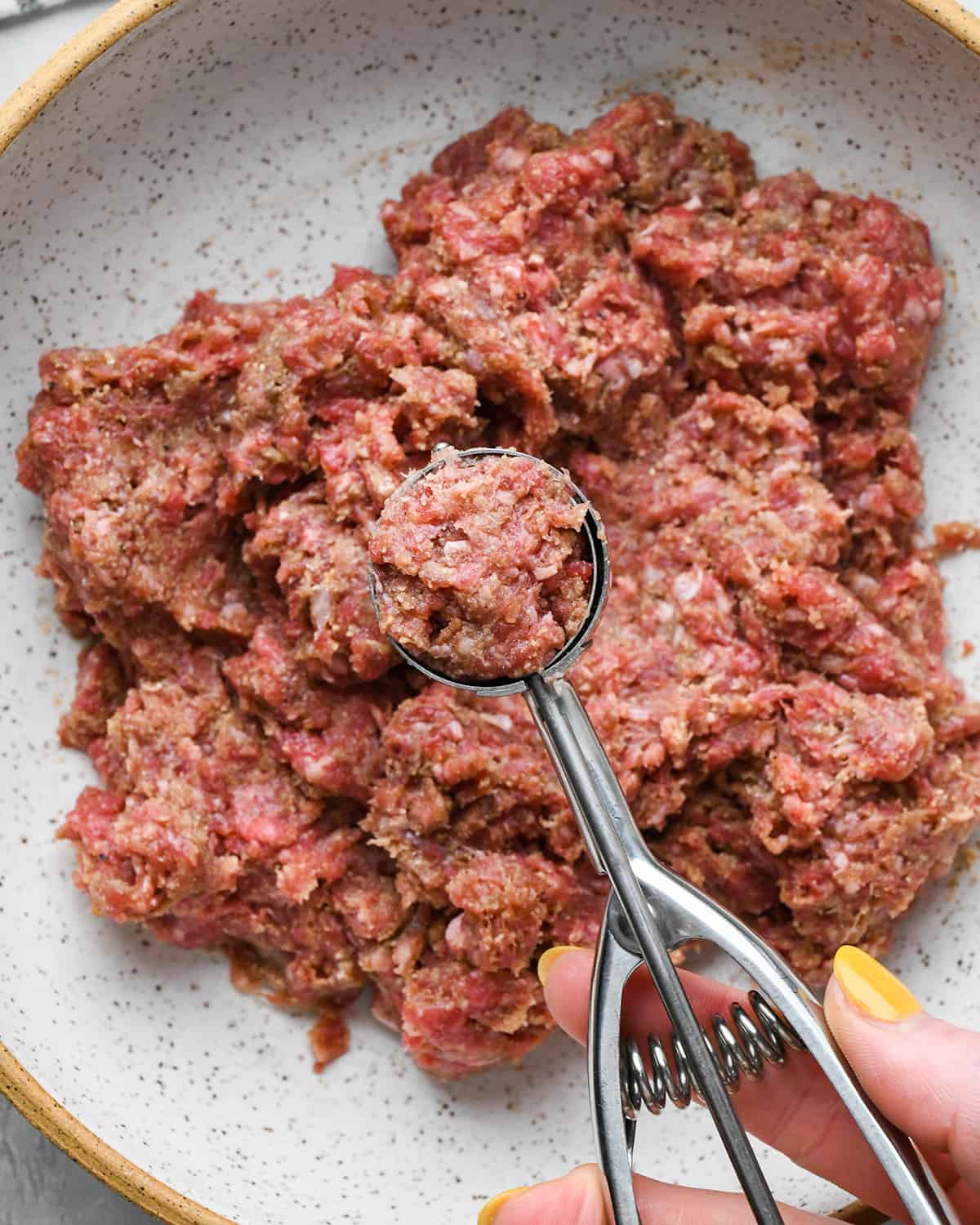 a cookie scoop measuring out a portion of Asian Meatballs