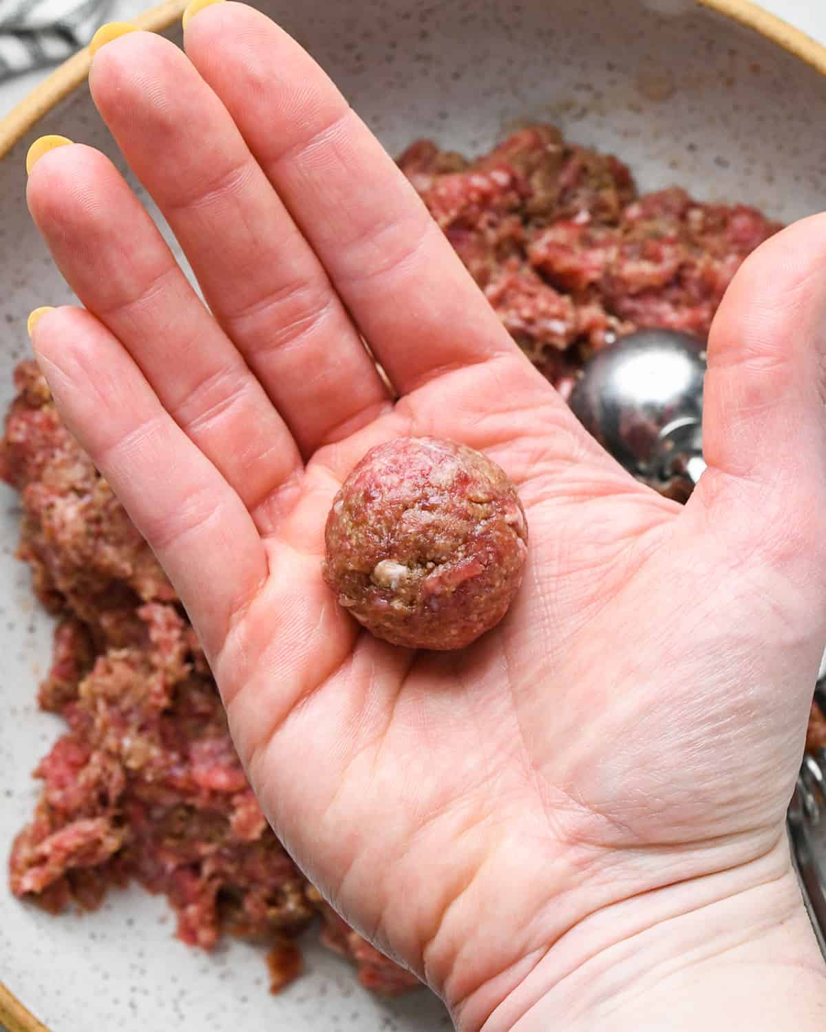 a hand rolling an Asian Meatball into a ball