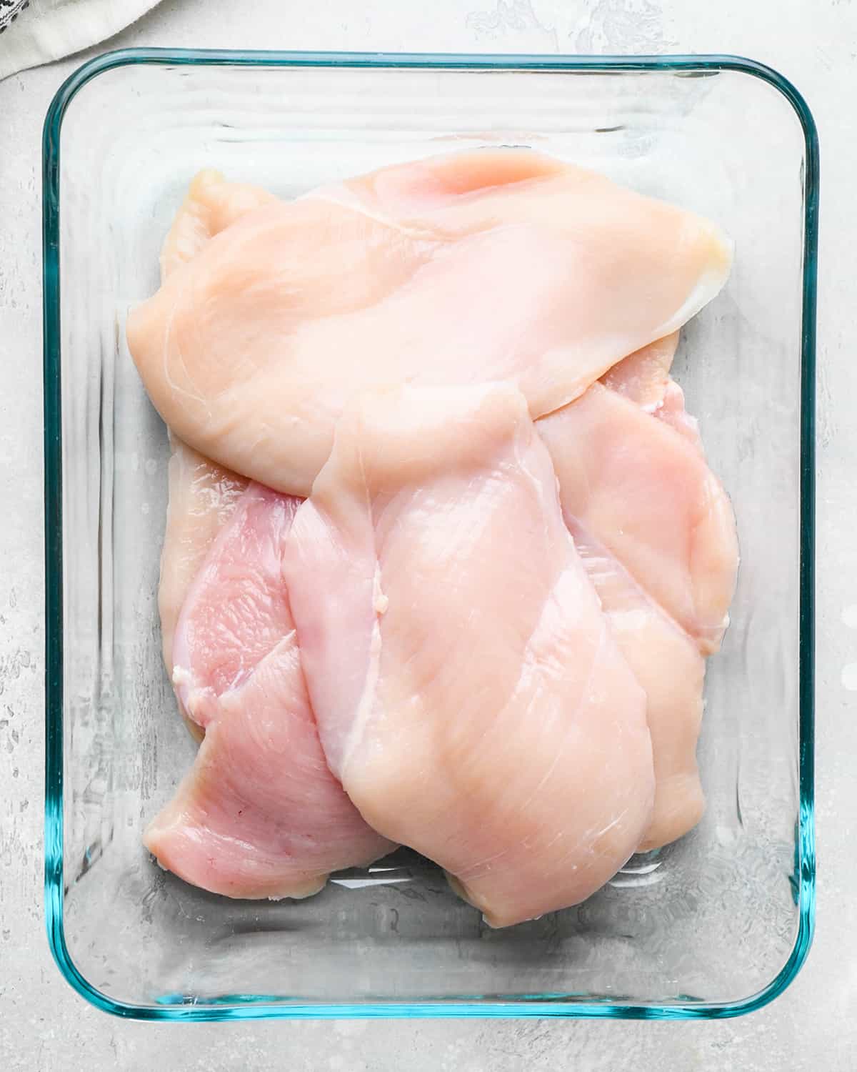 6 raw chicken breasts in a glass container