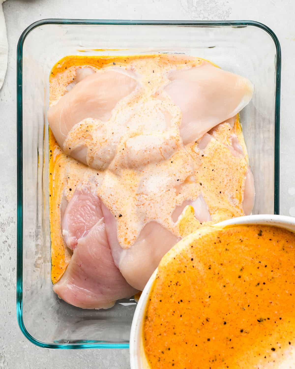 Buttermilk Chicken Marinade being poured over chicken in a glass container