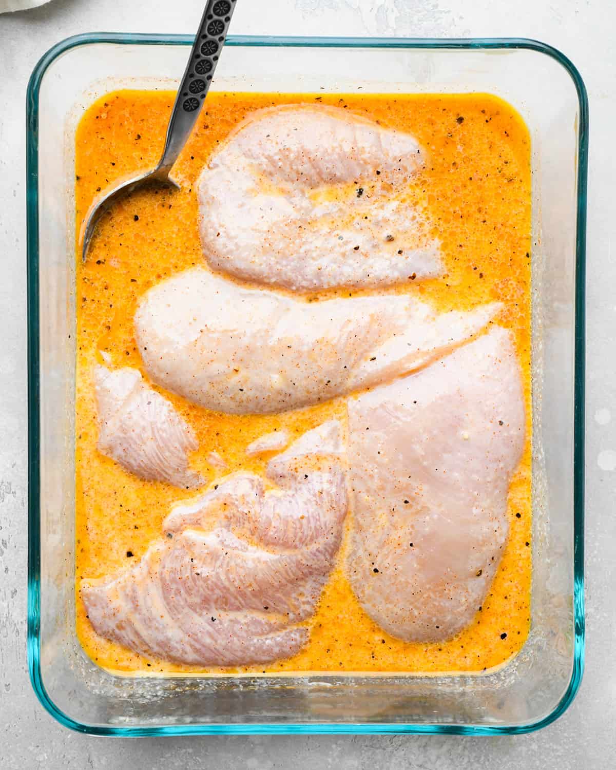 chicken in buttermilk marinade in a glass container