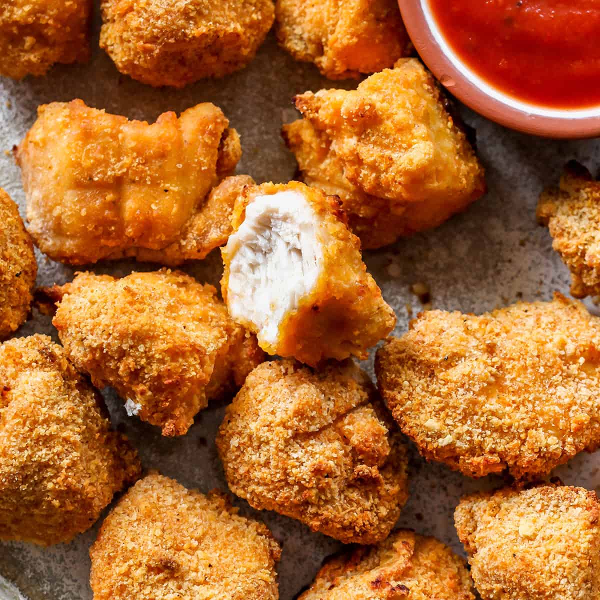 up close overhead view of Homemade Chicken Nuggets on a plate, one has a bite taken out of it