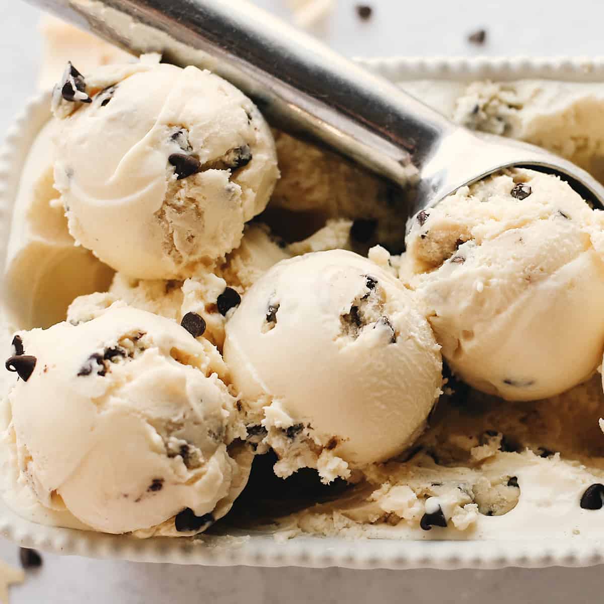 4 scoops of cookie dough ice cream in a container with a cookie scoop
