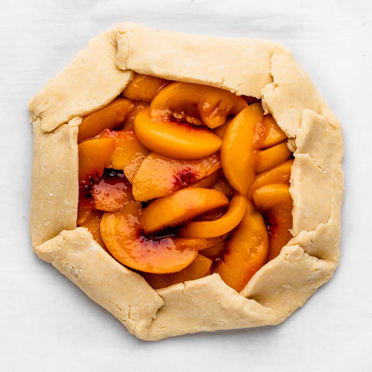 assembling peach galette - filling put into dough and dough edges pinched around the filling before baking