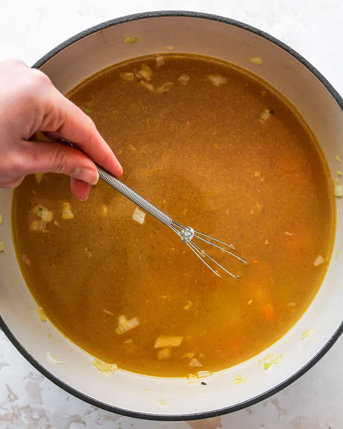 How to Make Chicken Noodle Soup - whisking in broth and chicken base 