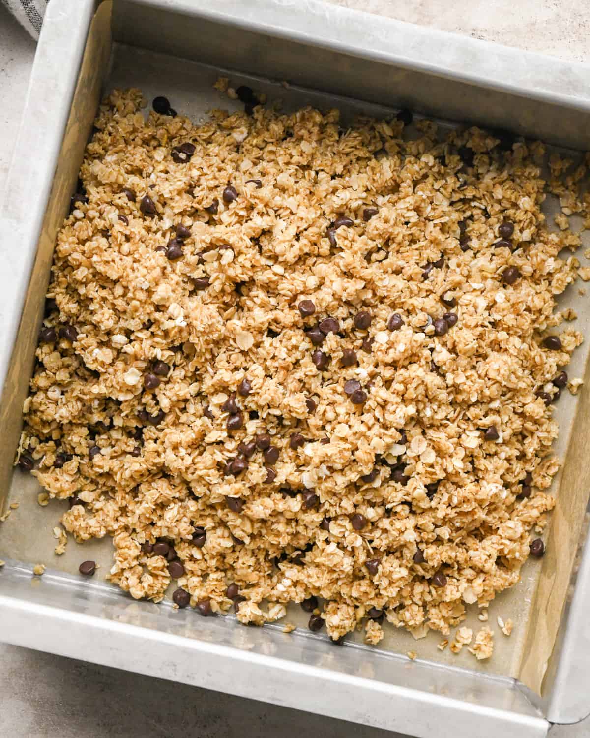 granola bar recipe mixture poured into a baking dish before spreading