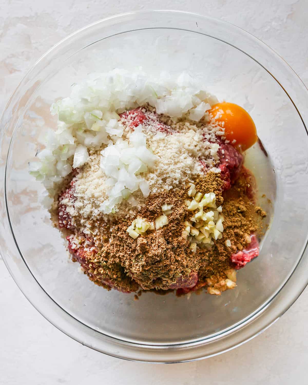 making Greek Meatballs, adding dry ingredients to meat mixture