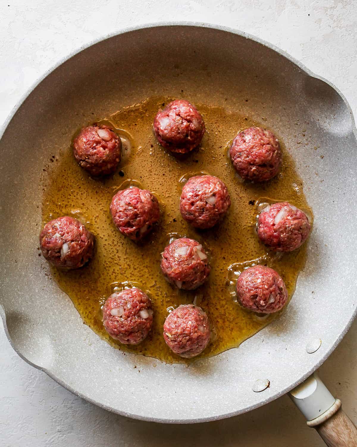 Greek Meatballs cooking on the first side in a fry pan