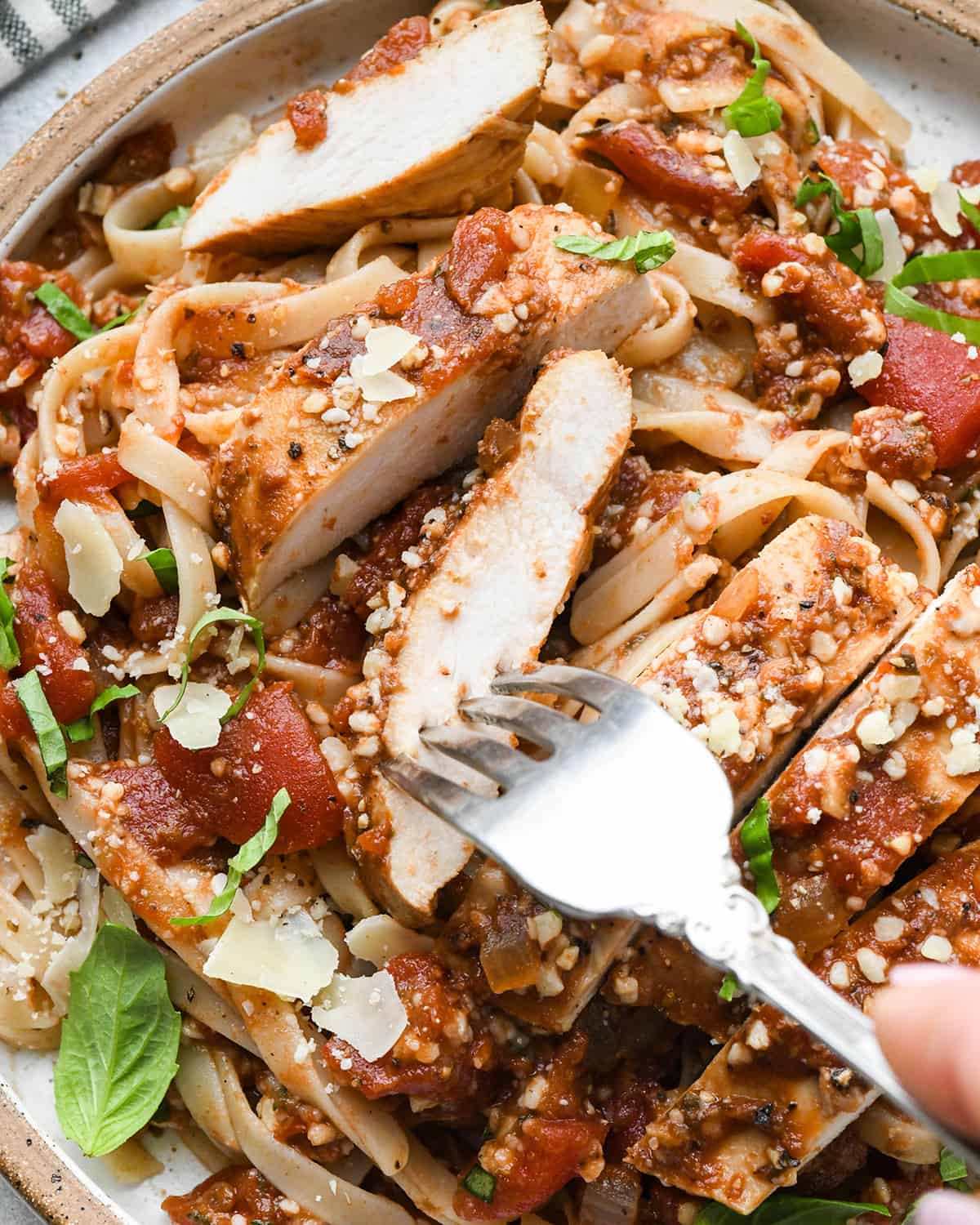 Slow Cooker Italian Chicken cut into strips on top of pasta on a plate