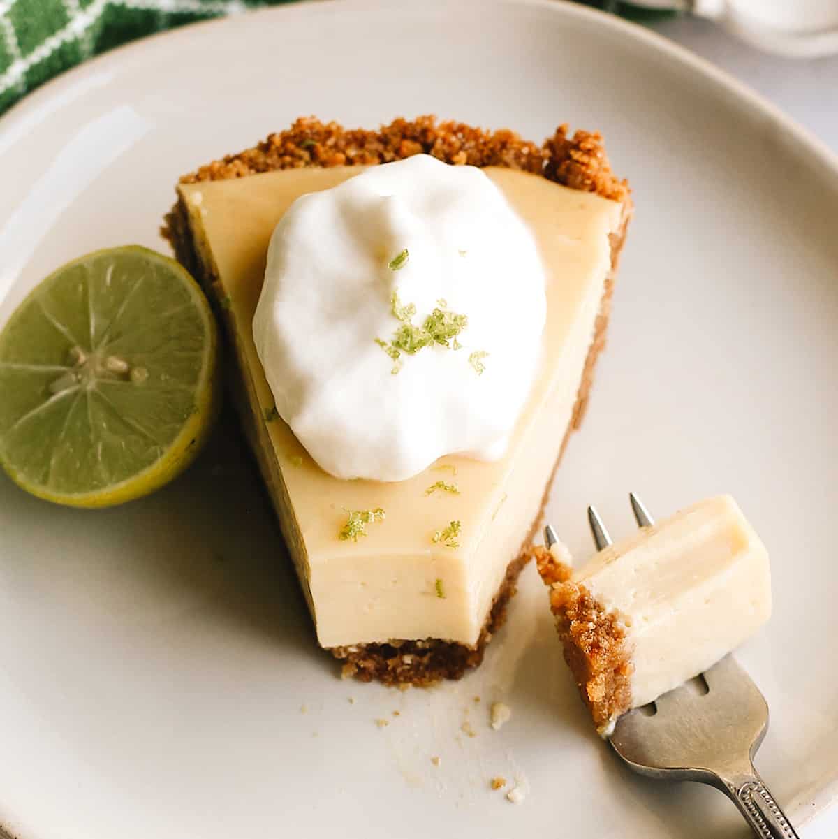 overhead photo of a piece of key lime pie on a plate with a bite taken out of it on a fork