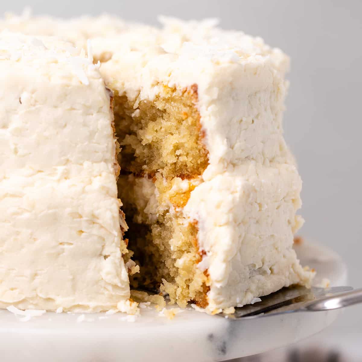 a slice of Coconut Cake being removed from the cake