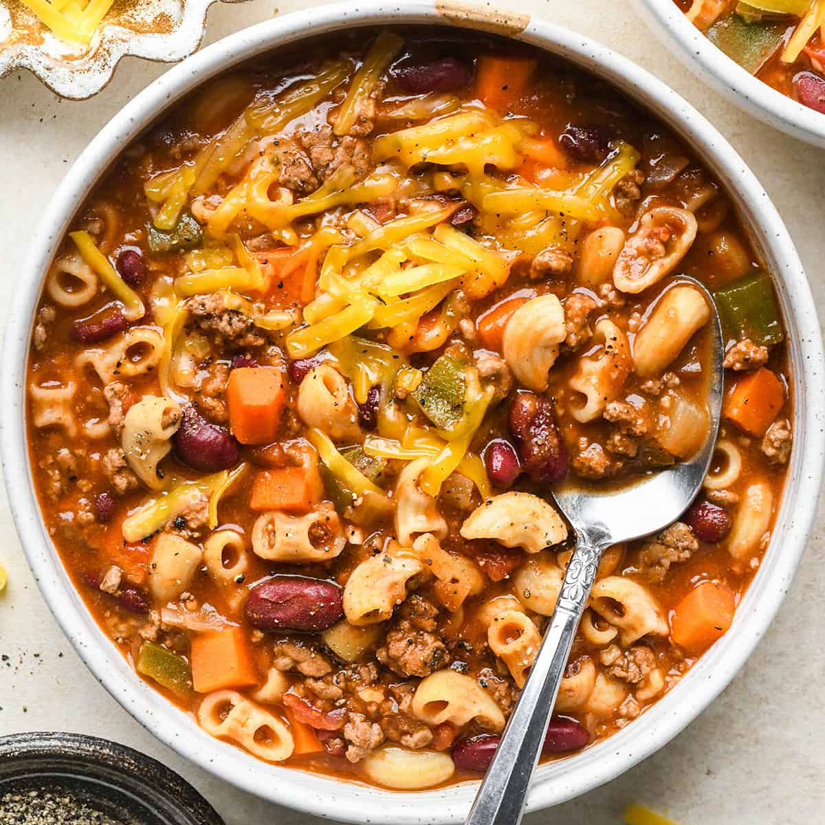 A bowl of Hamburger Soup with cheese on top and a spoon