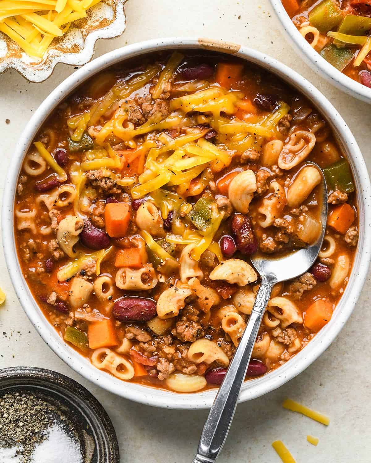 hamburger soup in a bowl with a spoon and cheese on top