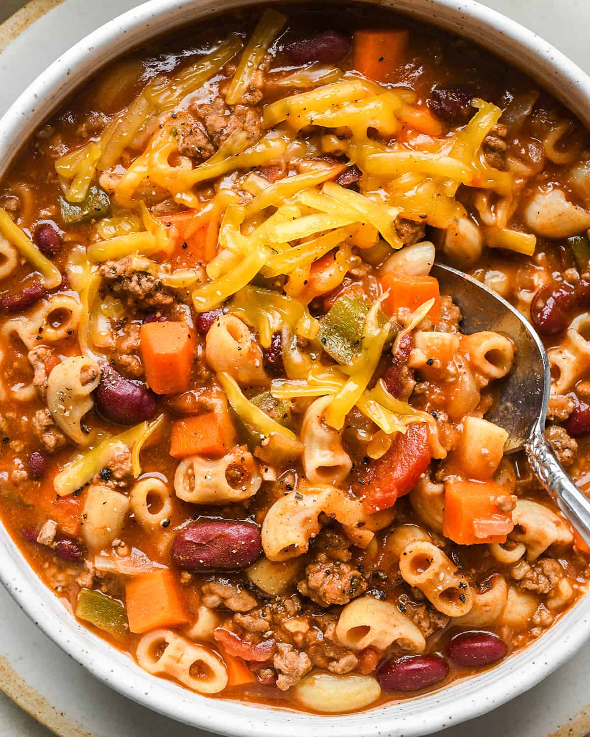 a spoon taking a scoop of Hamburger Soup wiht cheese on top 