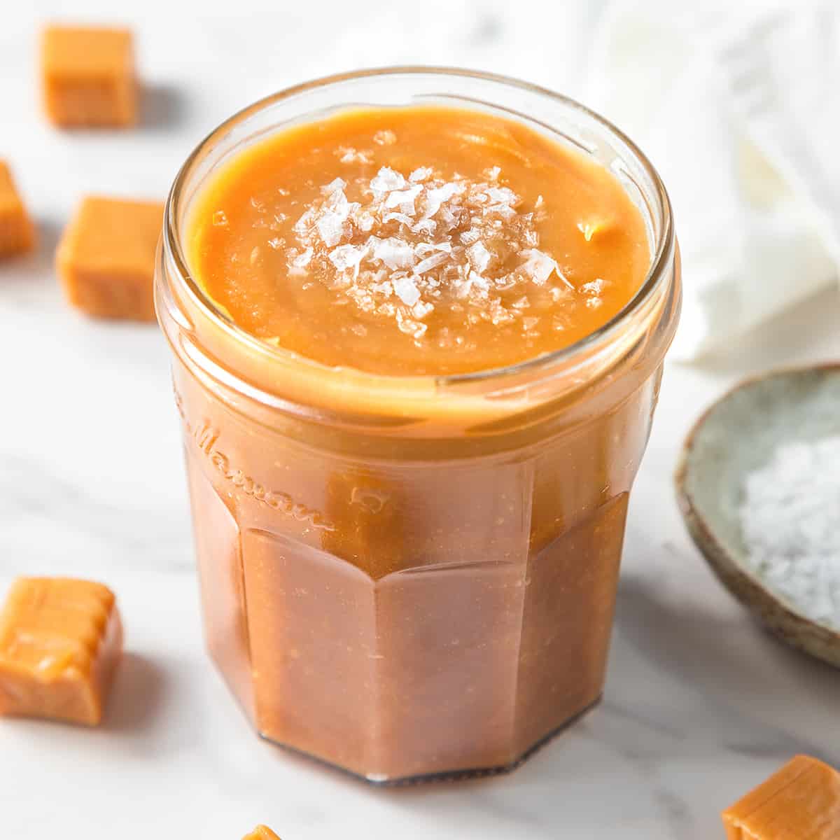 caramel sauce in a jar topped with flaky sea salt