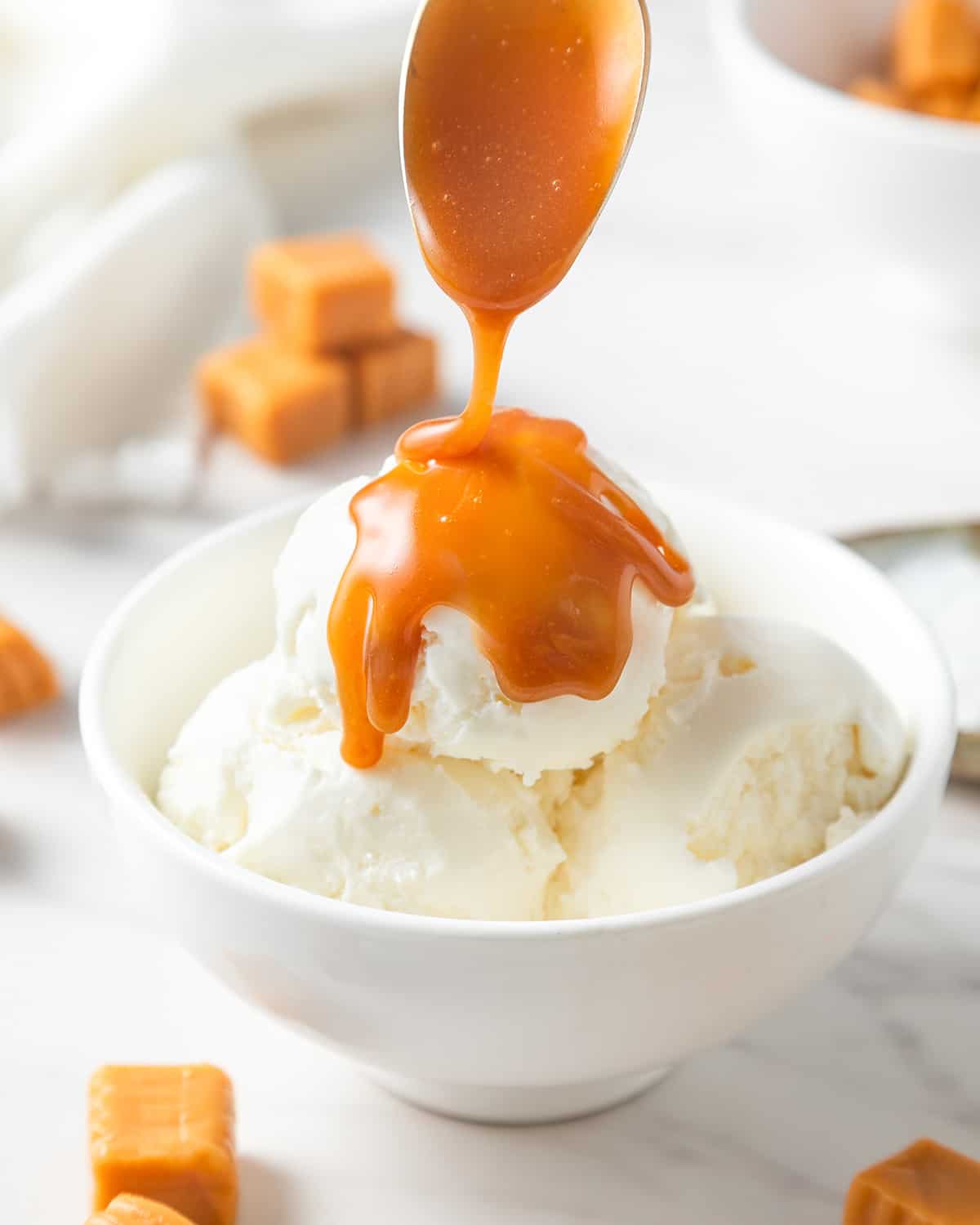Caramel Sauce being spooned over vanilla ice cream in a bowl