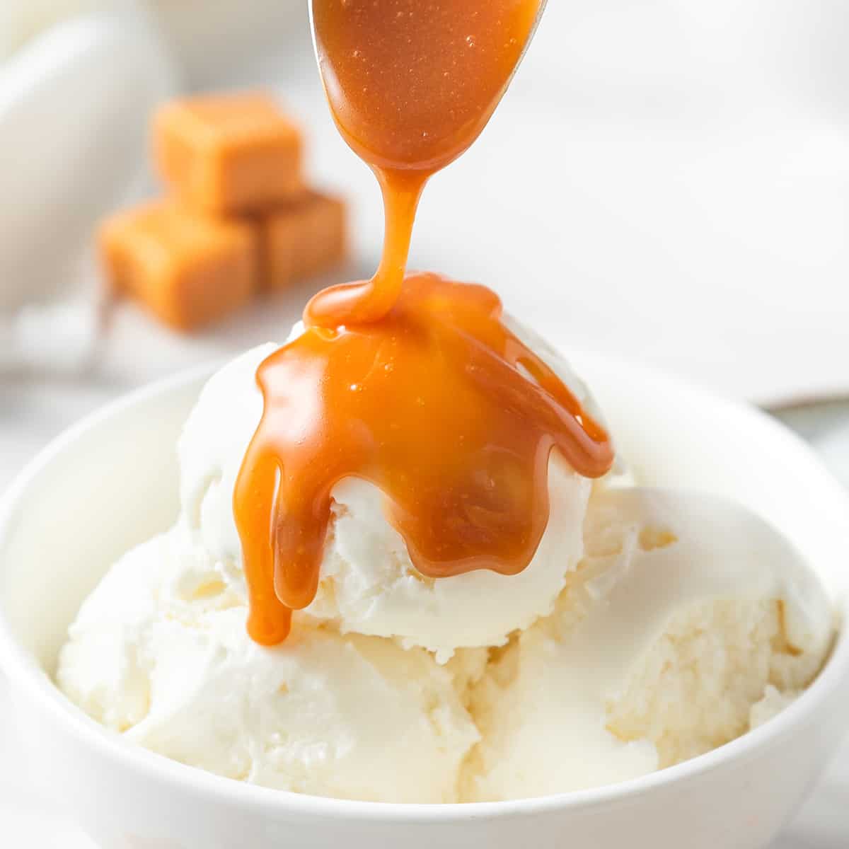homemade caramel sauce being poured over vanilla ice cream in a bwol