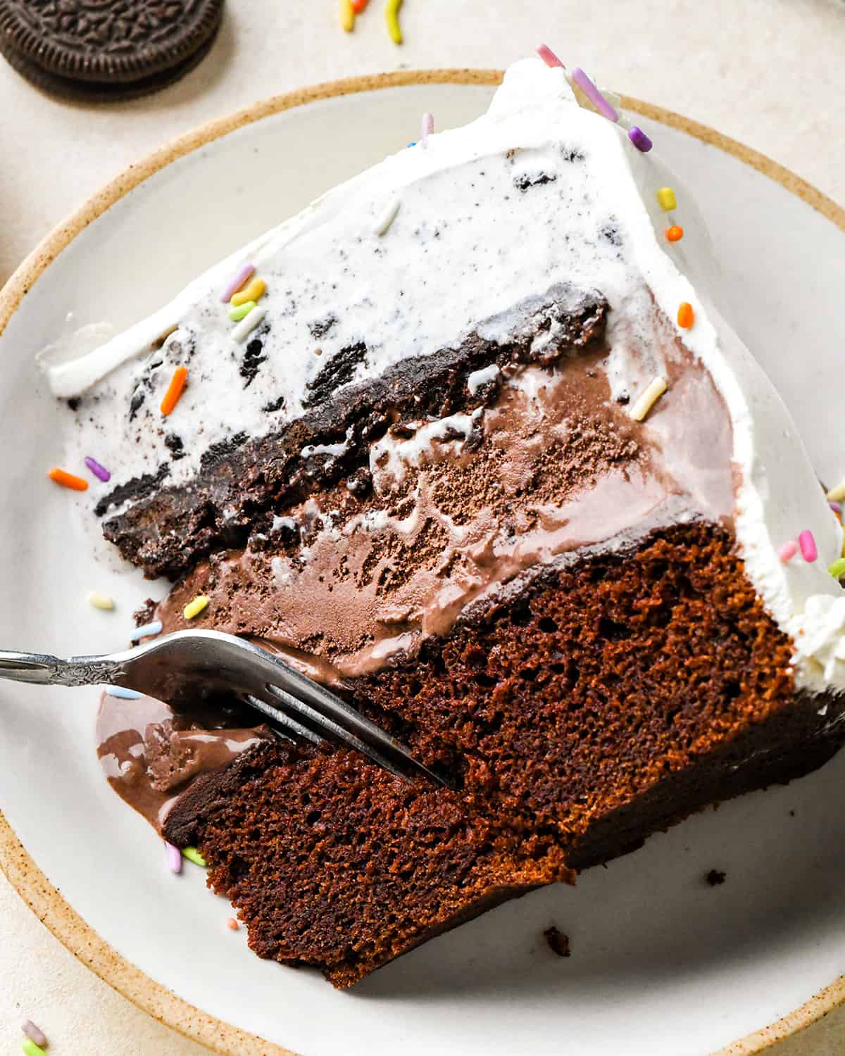 a fork taking a bite of a slice of ice cream cake on a plate