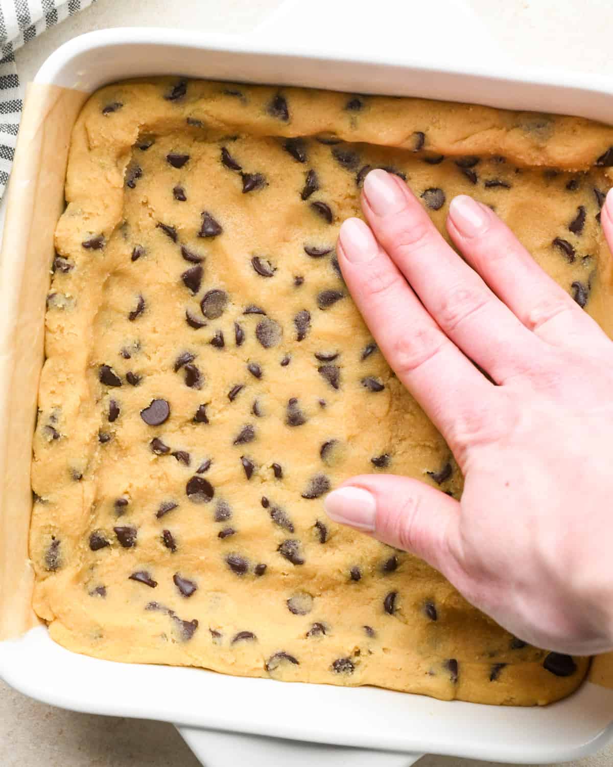 assembling Caramel Cookie Bars - pressing dough into the bottom of the baking dish