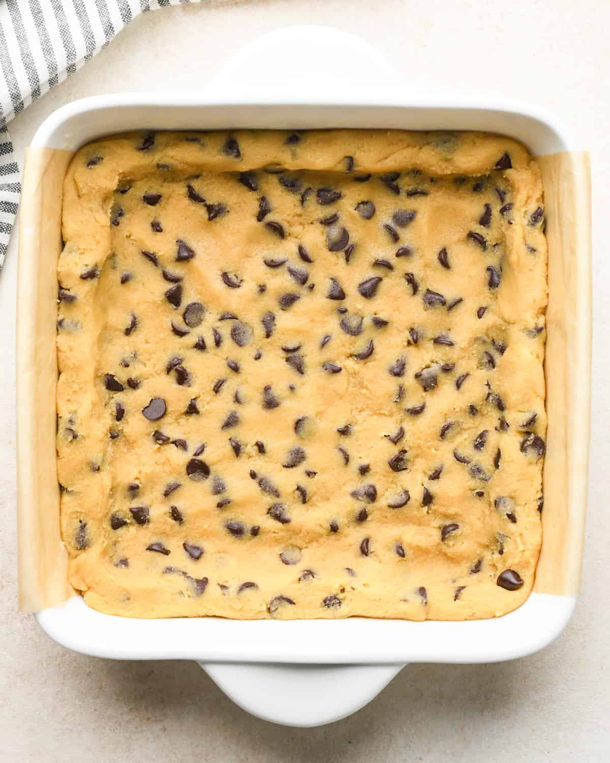 assembling Caramel Cookie Bars - dough pressed into the bottom of the baking dish