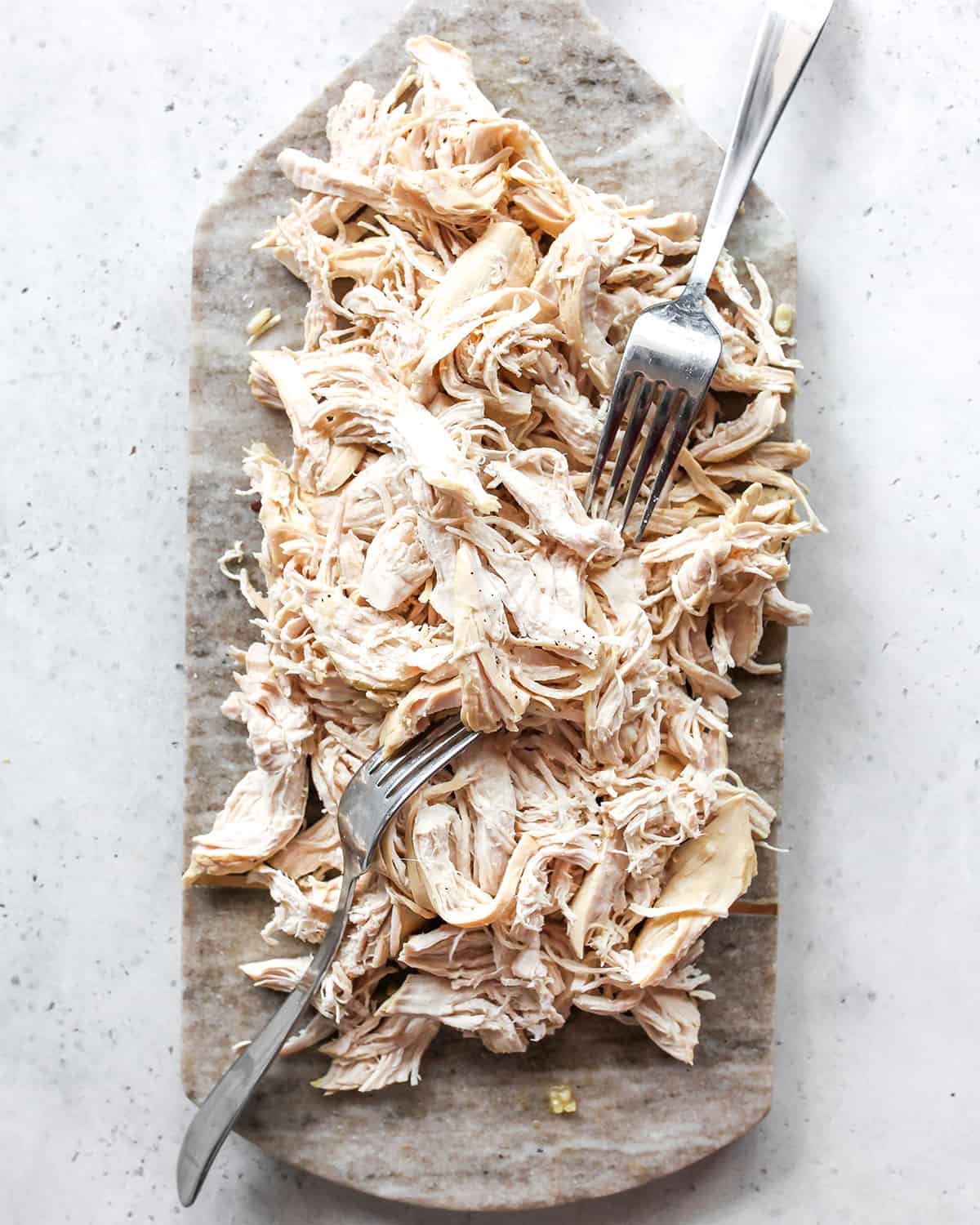 shredded chicken on a stone board with 2 forks