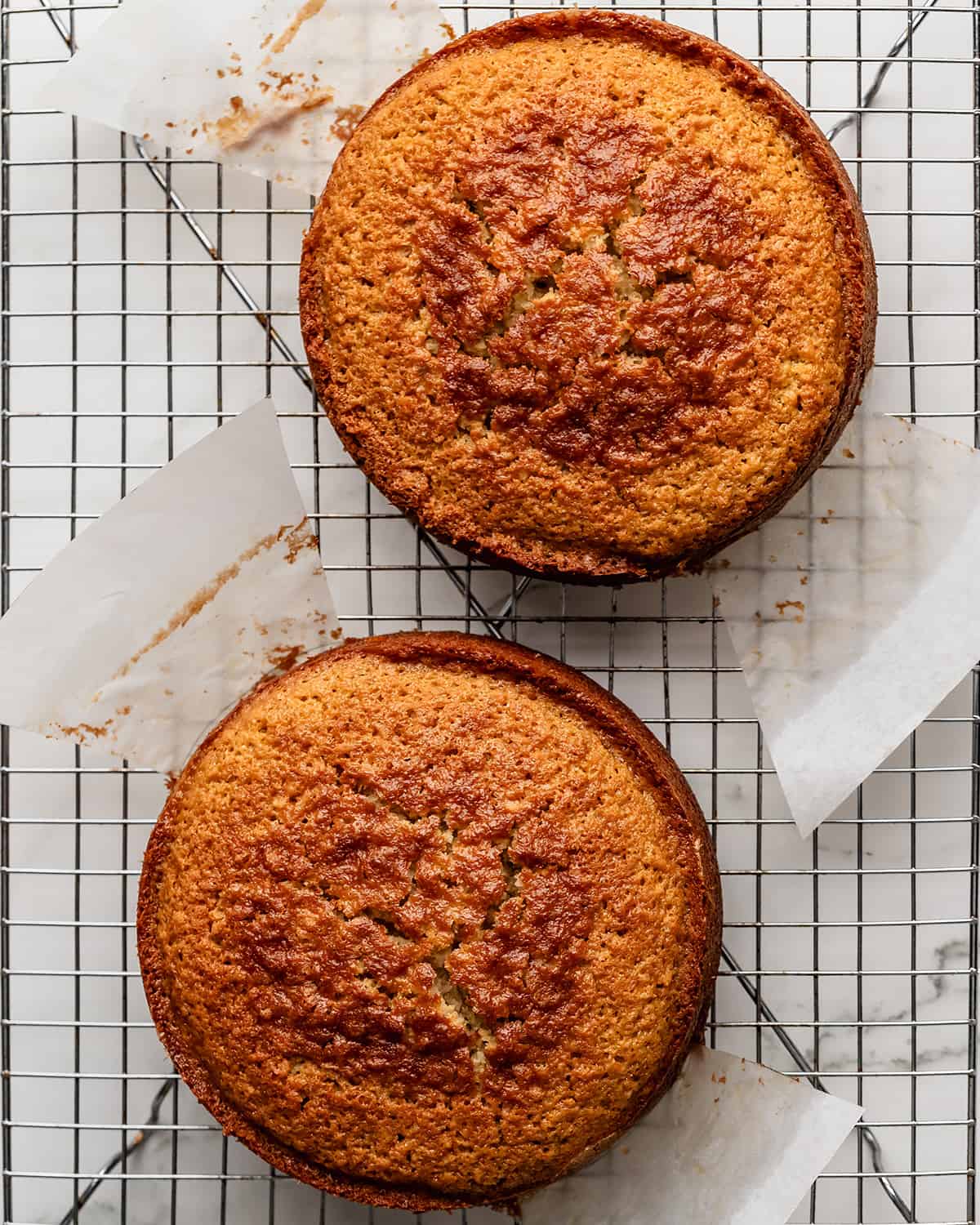 how to make coconut cake- two cake rounds on a wire cooling rack after being removed from the pans