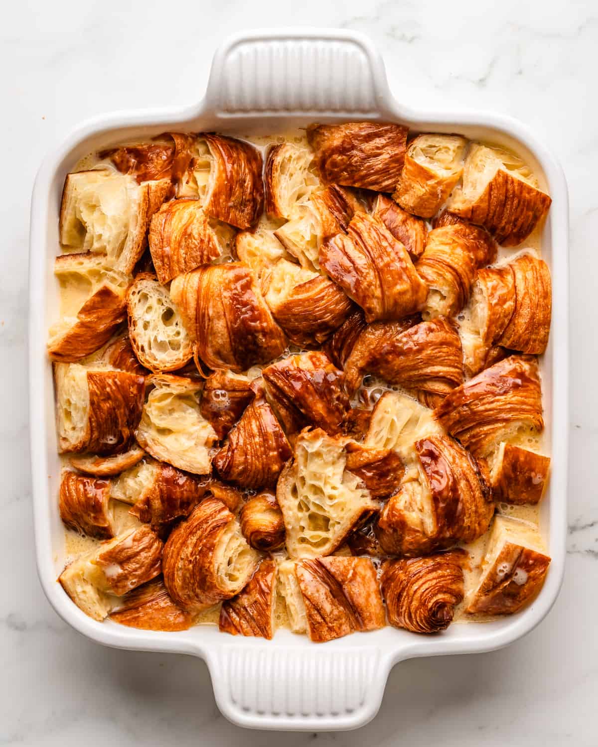 How to Make Croissant Bread Pudding - after pouring custard over croissant pieces in a baking dish