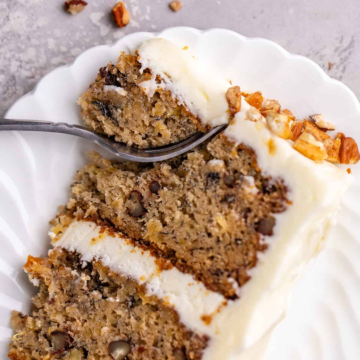 a fork taking a bite of hummingbird cake on a plate