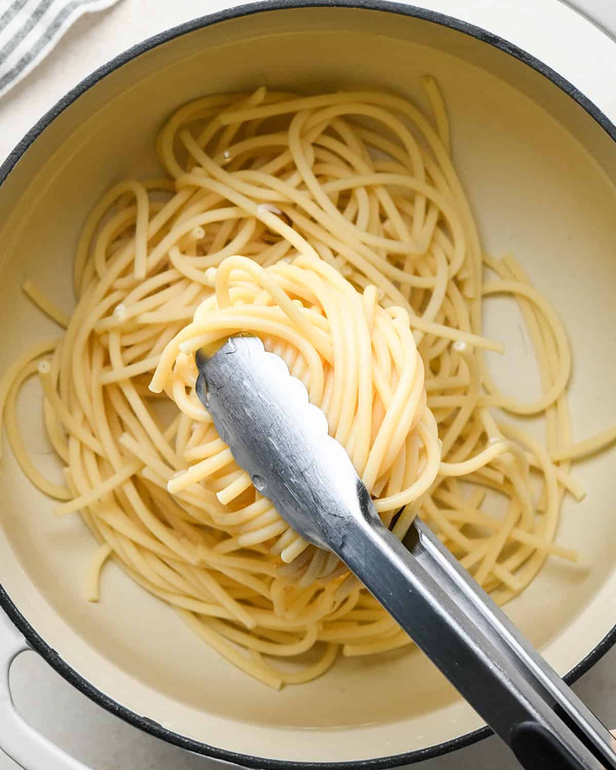 How to Make Parmesan Pasta - cooked pasta being removed from water with tongs 