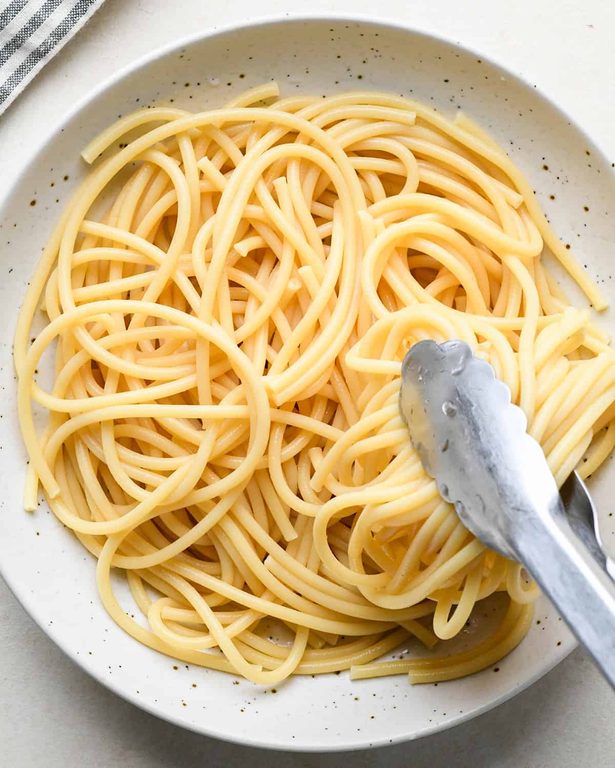 How to Make Parmesan Pasta - tongs putting pasta on a plate