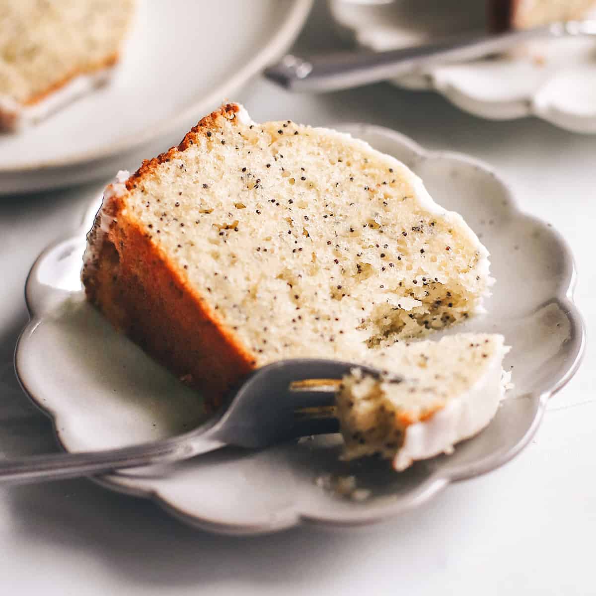 a fork taking a bite of a piece of Poppy Seed Cake on a plate