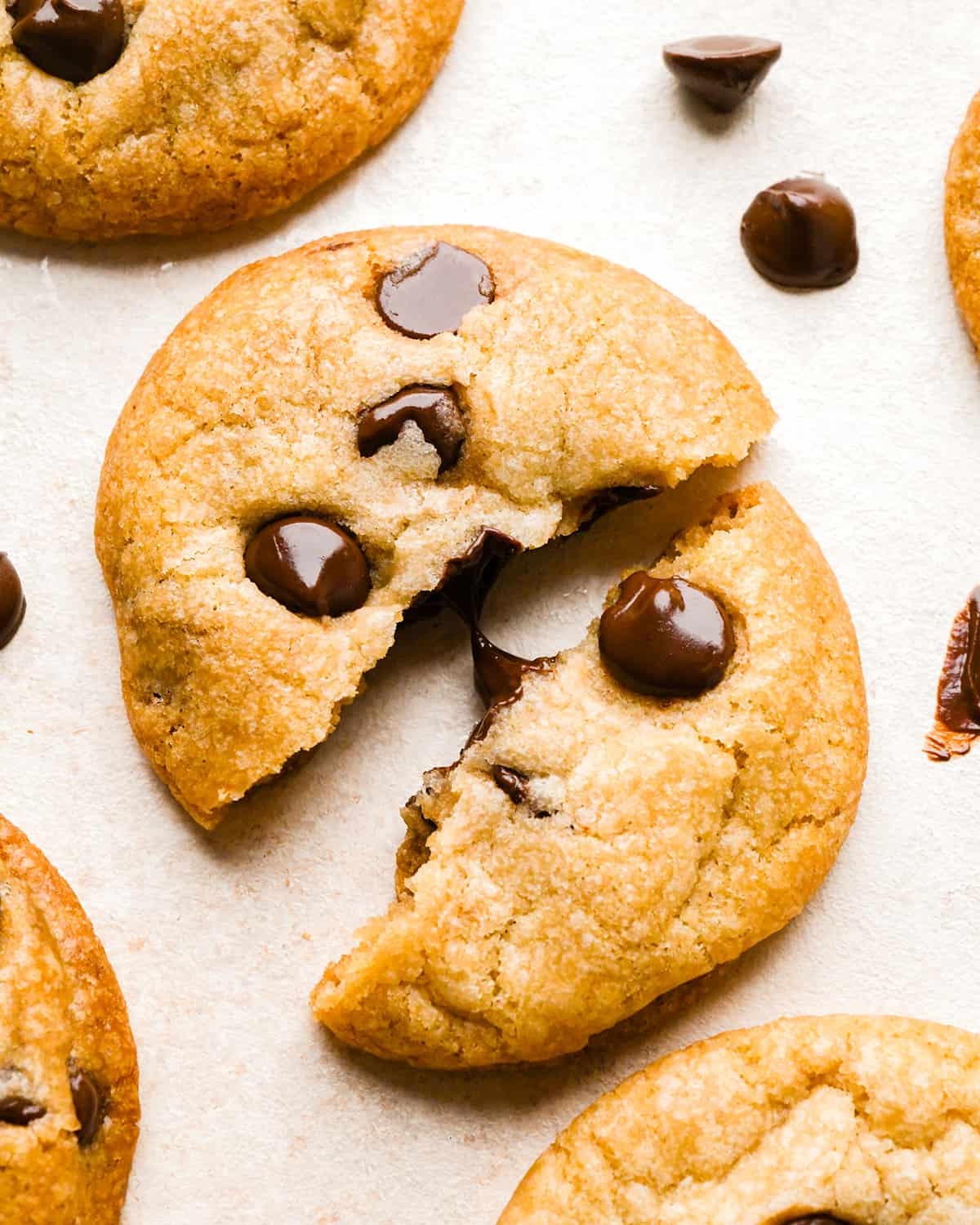 a Vegan Chocolate Chip Cookie torn in half with melty chocolate chips