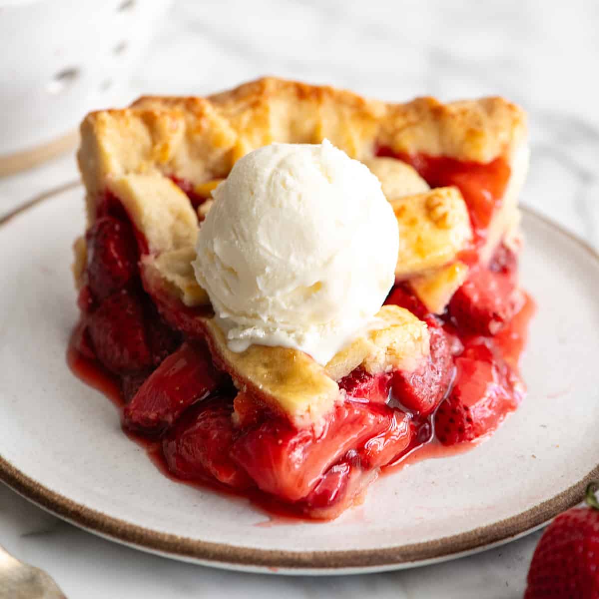 a slice of strawberry pie on a plate with vanilla ice cream on top