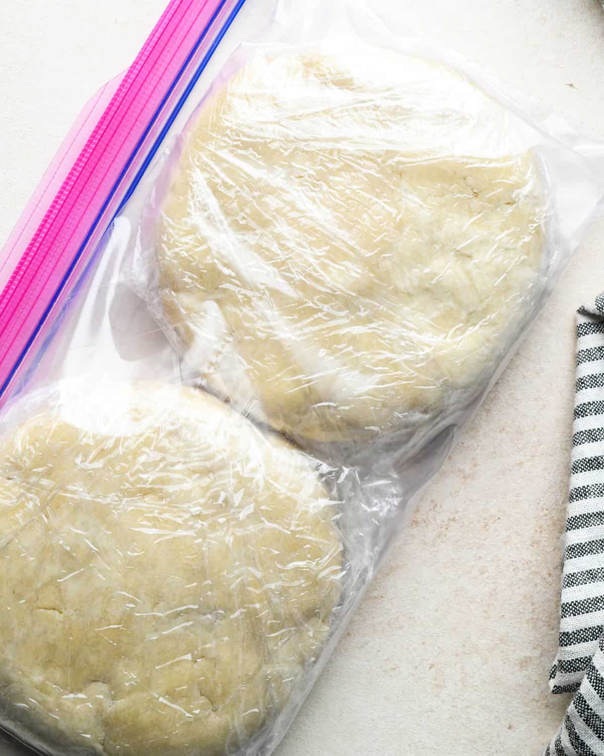 quiche crust dough formed into two round discs wrapped in plastic wrap in a plastic bag