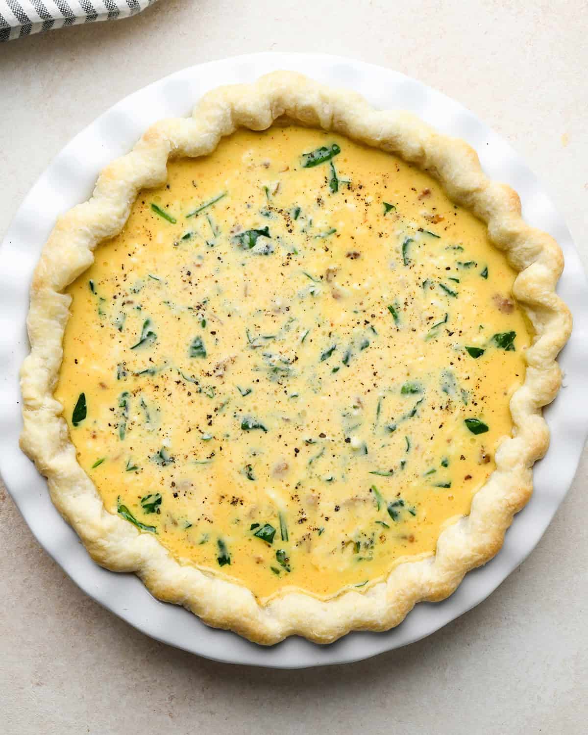 bacon spinach quiche in a pie dish before baking