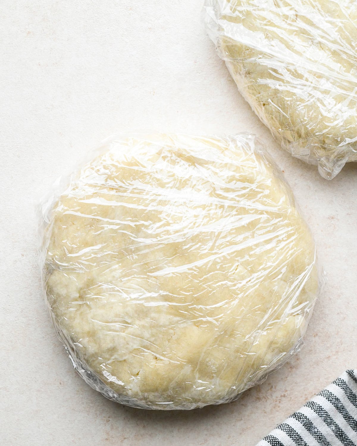 quiche crust dough formed into two round discs wrapped in plastic wrap
